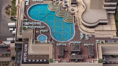 Photo for Rooftop swimming Pool with blue water in Dubai Marina aerial timelapse. Chairs and umbrellas around, bar with tables - Royalty Free Image
