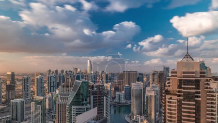 Photo for Dubai Marina skyscrapers and jumeirah lake towers view from the top aerial timelapse in the United Arab Emirates. Traffic on a road with cloudy sky at morning - Royalty Free Image