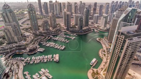 Foto de Dubai Marina rascacielos y torres de lago jumeirah vista desde la cima del timelapse aéreo durante todo el día con sombras que se mueven rápidamente en los Emiratos Árabes Unidos. Tráfico en una carretera - Imagen libre de derechos