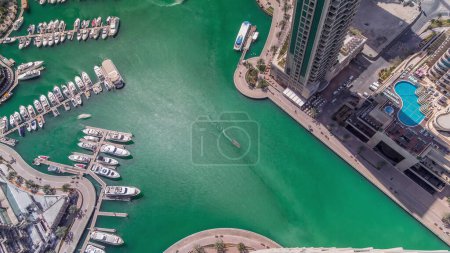 Photo for Dubai Marina harbor with modern yachts near waterfront aerial timelapse. Floating boats on canal surrounded towers and skyscrapers. - Royalty Free Image