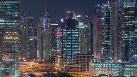 Foto de Dubai Marina y la noche aérea JLT timelapse vista superior de los rascacielos en Dubai, Emiratos Árabes Unidos. Torres modernas y tráfico en las calles - Imagen libre de derechos