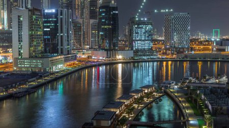 Téléchargez les photos : Ville nocturne avec gratte-ciel lumineux et petites maisons de luxe timelapse aérien près du canal à Business Bay, Dubaï, Émirats arabes unis - en image libre de droit