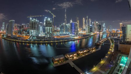 Photo for Night city with lights from illuminated skyscrapers near canal and Downtown towers in the background aerial timelapse in Business Bay, Dubai, United Arab Emirates - Royalty Free Image