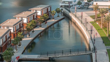 Téléchargez les photos : Petites maisons de luxe près du canal avec des yachts et des palmiers et beau pont à Business Bay, Dubaï, Émirats arabes unis timelapse aérienne - en image libre de droit