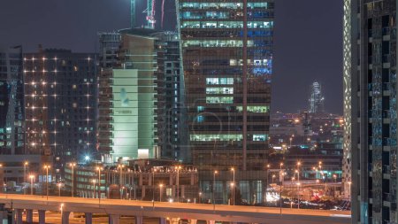 Téléchargez les photos : Belles lumières dans la ville moderne la nuit timelapse aérien avec d'énormes grues près des routes à Business Bay, Dubaï, Émirats arabes unis - en image libre de droit