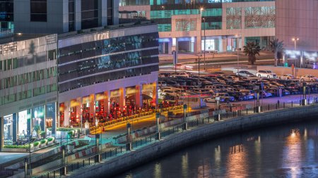 Téléchargez les photos : Parking près des restaurants de la côte avec des paumes et des lumières vives près du canal timelapse aérien à Business Bay, Dubai, Émirats arabes unis - en image libre de droit