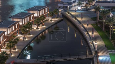 Téléchargez les photos : Maisons de luxe près du canal avec palmiers et beau pont aérien timelapse la nuit à Business Bay, Dubai, Émirats arabes unis - en image libre de droit