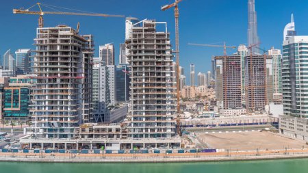 Téléchargez les photos : Vue aérienne d'un gratte-ciel en construction avec d'énormes grues timelapse à Dubaï. Quartier des affaires avec le centre-ville sur un fond. Émirats arabes unis - en image libre de droit