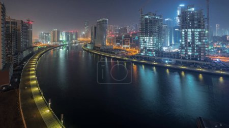 Téléchargez les photos : Vue aérienne du canal attrayant entre les gratte-ciel modernes et le chantier de construction de nuit au jour le jour passage timelapse à Business Bay, Dubaï, Émirats arabes unis - en image libre de droit