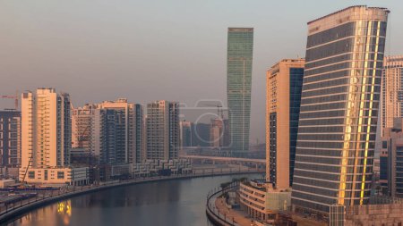 Téléchargez les photos : Vue aérienne du canal attrayant entre les gratte-ciel modernes tôt le matin pendant le lever du soleil timelapse dans Business Bay avec des ombres se déplaçant rapidement, Dubai, Émirats arabes unis - en image libre de droit