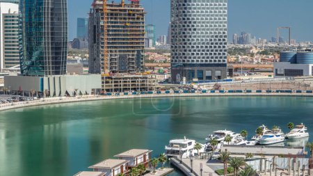 Téléchargez les photos : Gratte-ciel près du canal avec eau bleue et yachts de luxe. Construire avec des tours à Business Bay, Dubai, Émirats arabes unis timelapse aérien - en image libre de droit