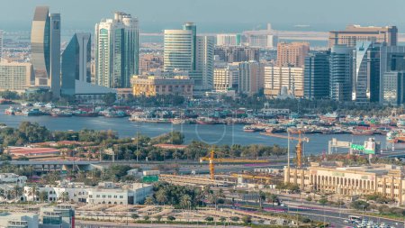 Téléchargez les photos : Vue aérienne des nouveaux gratte-ciel modernes Timelapse près de la rivière avec des navires en bois par une journée ensoleillée avec un ciel bleu à Deira, Dubaï, Émirats arabes unis - en image libre de droit