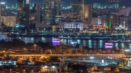 Téléchargez les photos : Vue aérienne de la ville et de la rivière avec des navires éclairés flottants et des yachts timelapse la nuit à Deira et Dubai Creek, Émirats arabes unis - en image libre de droit
