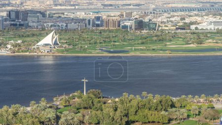 Foto de Vista del campo de golf en la lujosa ciudad de Dubái cerca del arroyo azul Aerial Timelapse en Deira con aeropuerto sobre un fondo en un día soleado y cielo azul, Emiratos Árabes Unidos - Imagen libre de derechos