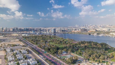 Téléchargez les photos : Vue panoramique aérienne des bâtiments à Deira et Dubai Creek par une journée ensoleillée avec des nuages sur un ciel bleu Timelapse et des gratte-ciel sur un fond à Dubaï, Émirats arabes unis - en image libre de droit