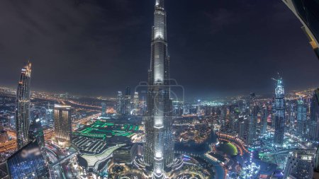 Téléchargez les photos : Vue panoramique sur Dubaï centre-ville avec centre commercial, fontaines et Burj Khalifa timelapse de nuit aérienne. gratte-ciel modernes et ciel nuageux après le coucher du soleil - en image libre de droit