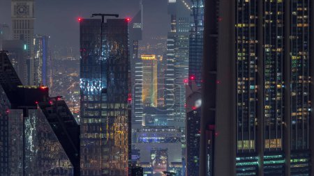 Téléchargez les photos : Dubai International Financial Centre district avec gratte-ciel modernes éclairés nuit timelapse. Vue aérienne du centre-ville avec circulation dans les rues - en image libre de droit