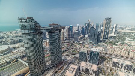 Photo for Dubai International Financial Centre district with modern skyscrapers timelapse. Aerial view from Downtown with traffic on streets and construction site - Royalty Free Image