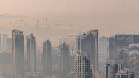 erstaunliche Luftaufnahme Dubais Wolkenkratzer in der Innenstadt im Zeitraffer mit Springbrunnen und Morgennebel, Dubai, vereinigte arabische Emirate. Moderne Türme und Großbaustelle mit vielen Kränen