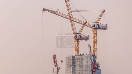 Téléchargez les photos : Bâtiment de grande hauteur en construction avec grue de construction jaune à Dubaï timelapse. Vue aérienne le matin dans le centre-ville - en image libre de droit