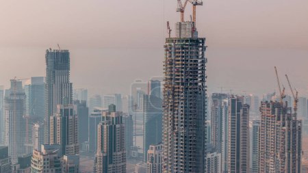 Foto de Avance de la construcción de un nuevo rascacielos moderno en el timelapse aéreo de la ciudad de Dubai, Emiratos Árabes Unidos. Grúas y equipos de construcción en el centro - Imagen libre de derechos