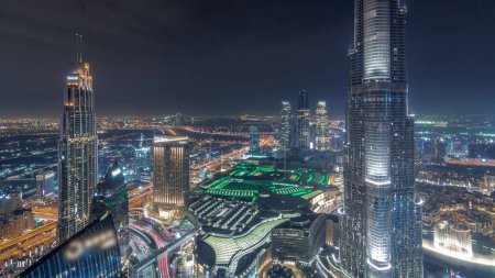 Téléchargez les photos : Vue panoramique sur l'horizon du centre-ville de Dubaï avec centre commercial, fontaines et Burj Khalifa timelapse aérien pendant toute la nuit avec des lumières éteintes. gratte-ciel modernes et ciel nuageux - en image libre de droit