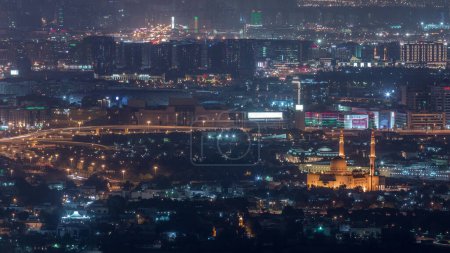 Foto de Vista aérea del barrio de Zabeel y Dubai arroyo con edificios típicos antiguos y modernos timelapse noche. Mezquita y tráfico en la intersección. Vista desde la azotea del rascacielos. Dubai, Emiratos Árabes Unidos - Imagen libre de derechos