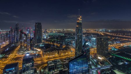 Foto de Dubai International Financial Centre distrito con rascacielos modernos iluminados noche a día timelapse transición. Vista aérea desde el centro con tráfico en las calles antes del amanecer - Imagen libre de derechos