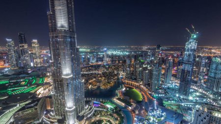 Foto de Vista panorámica del centro de Dubái con centro comercial, fuentes y timelapse nocturno aéreo Burj Khalifa. Rascacielos modernos y cielo nublado después del atardecer - Imagen libre de derechos