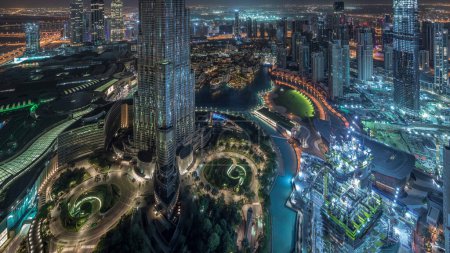 Téléchargez les photos : Vue aérienne imprenable sur les gratte-ciels du centre-ville de Dubaï nuit à jour transition timelapse avec fontaines, Dubaï, Émirats arabes unis. Tours modernes éclairées et chantier de construction avant le lever du soleil - en image libre de droit