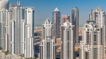 Foto de Moderno complejo residencial y de oficinas con muchas torres aéreas timelapse en Business Bay, Dubai, Emiratos Árabes Unidos. Cielo azul y tráfico en las carreteras - Imagen libre de derechos