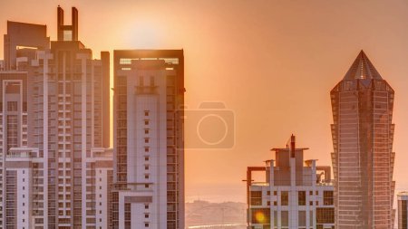 Téléchargez les photos : Coucher de soleil derrière la timelapse aérienne moderne du complexe résidentiel et de bureaux à Business Bay, Dubaï, Émirats arabes unis. Ciel orange et soleil derrière le gratte-ciel - en image libre de droit