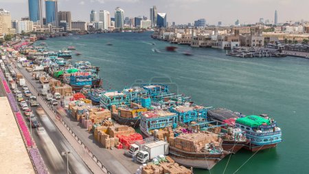 Photo for Loading a ship in port timelapse in Dubai, Deira creek, UAE. Aerial top view from above with many old boats and cargo ships - Royalty Free Image