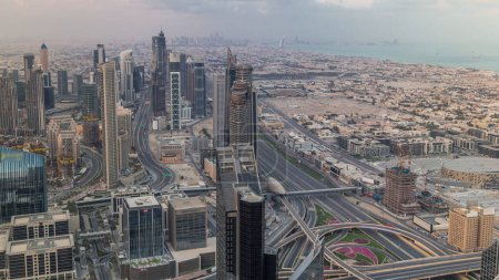 Téléchargez les photos : Dubaï Paysage urbain futuriste du centre-ville avec de nombreux gratte-ciel et une baie d'affaires aérienne timelapse. Panorama du matin au lever du soleil avec tours modernes et construction depuis le toit - en image libre de droit