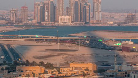 Photo for Construction of new skyscrapers in Dubai Creek Harbor aerial timelapse during sunset with long shadows. Dubai - UAE. Top view from Dubai downtown with traffic on a highway - Royalty Free Image