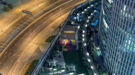 Foto de Vista de la carretera con muchos coches en el tráfico y la piscina cerca de rascacielos con palmeras timelapse noche en el centro de Dubai, Dubai, Emiratos Árabes Unidos - Imagen libre de derechos