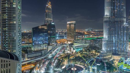 Téléchargez les photos : Dubaï gratte-ciel du centre-ville vue aérienne incroyable la nuit timelapse avec des fontaines et la circulation dans les rues, Dubaï, Émirats arabes unis. Tours modernes éclairées et chantier de construction - en image libre de droit