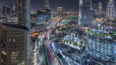 Foto de Vista panorámica del centro de Dubái con centro comercial, fuentes y horario nocturno aéreo Burj Khalifa con tráfico. Rascacielos iluminados modernos y obras de construcción - Imagen libre de derechos