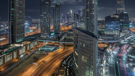 Téléchargez les photos : Vue aérienne de nouvelles tours et de grands bâtiments avec des routes achalandées timelapse de nuit à Dubaï Centre-ville d'en haut avec la circulation sur l'autoroute et le quartier financier en arrière-plan, Dubaï, Émirats arabes unis - en image libre de droit
