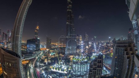 Panoramic skyline view of Dubai downtown before sunrise with mall, fountains and Burj Khalifa aerial night to day transition timelapse. Modern skyscrapers and construction site