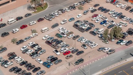 Photo for Aerial view full cars at large outdoor parking lots timelapse in Dubai, UAE. Crowded parking lot on sand with other cars try getting in and out, finding parking space. - Royalty Free Image