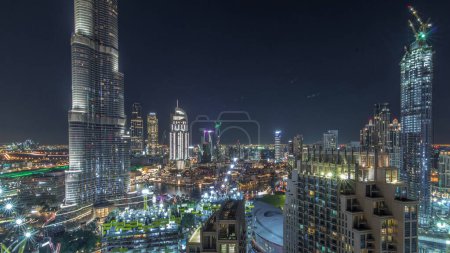 Téléchargez les photos : Vue panoramique sur l'horizon du centre-ville de Dubaï avec centre commercial, fontaines et Burj Khalifa timelapse aérien pendant toute la nuit avec des lumières qui s'éteignent. gratte-ciel modernes éclairés et chantier de construction - en image libre de droit