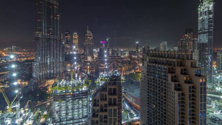 Panoramic skyline view of Dubai downtown before sunrise with mall, fountains and Burj Khalifa aerial night to day transition timelapse. Modern skyscrapers and construction site