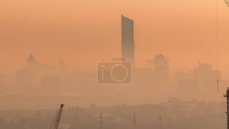 Vue aérienne du ruisseau Dubai avec la ville des festivals pendant le lever du soleil timelapse. Brouillard matinal orange et chantier de construction du centre-ville. Dubaï - EAU
