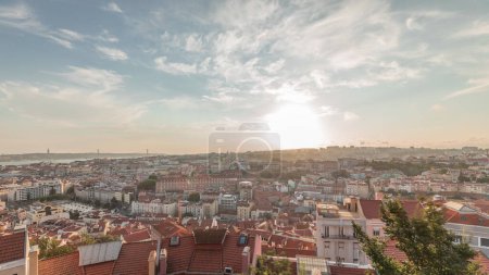 Panorama mit der berühmten Luftaufnahme von Lissabon vom touristischen Aussichtspunkt Miradouro da Senhora do Monte der Alfama und der Mauraria Altstadt im Zeitraffer, 25. April Brücke bei Sonnenuntergang. Lissabon, Portugal