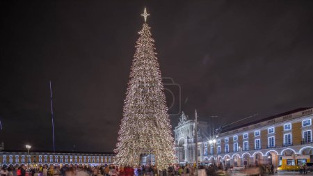 Foto de Panorama que muestra la plaza del Comercio iluminada y decorada en Navidad en Lisboa noche timelapse. Plaza Commercio con árbol de Navidad y gente turistas multitud alrededor. Tiempo de vacaciones. Portugal - Imagen libre de derechos