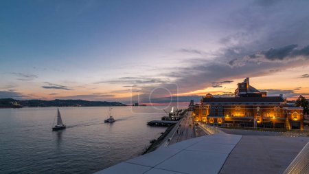Foto de Vista panorámica del timelapse de transición día a noche frente al mar. Famoso monumento a orillas del río Tajo en Lisboa con coloridas nubes - Imagen libre de derechos