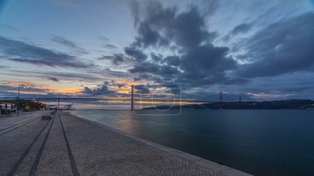 Lisbon city sunrise with April 25 bridge panoramic timelapse, River and waterfront early morning. Colorful cloudy sky