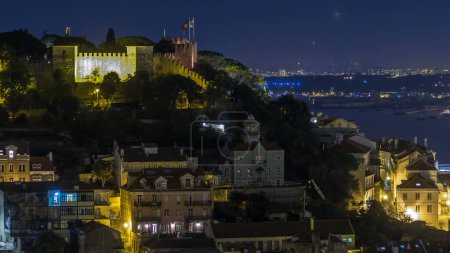 Photo for Lisbon aerial overview of city center with illuminated castle on hill at Autumn night timelapse, Portugal. Top view from Miradouro da Nossa Senhora do Monte viewpoint - Royalty Free Image