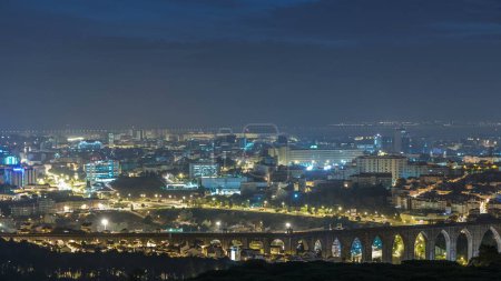 Téléchargez les photos : Vue panoramique de l'aube sur Lisbonne et l'Almada d'un point de vue à Monsanto nuit à la transition de jour timelapse. Vue aérienne avec circulation et aqueduc des eaux libres - en image libre de droit